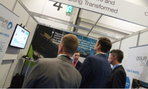 A group of delegates huddle round the Assure360 stand at Expo